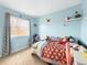 Bright, whimsical bedroom with blue walls, a playful soccer-themed quilt, and natural light from the window at 10781 Moore St, Westminster, CO 80021
