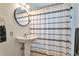 Compact bathroom featuring a pedestal sink and a shower with a black and white patterned curtain at 6484 Kendall St, Arvada, CO 80003