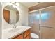 Bathroom with a sink and shower, featuring a round mirror, and brown tiling at 6484 Kendall St, Arvada, CO 80003