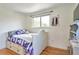 Cozy bedroom with a white frame bed featuring storage drawers and a purple quilt, illuminated by a window at 6484 Kendall St, Arvada, CO 80003