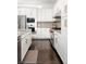 Bright kitchen features dark wood floors, white cabinets, stainless steel appliances and gray backsplash at 89 Oneida St, Denver, CO 80230