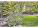 Spacious backyard with mature trees, a stone-lined pond, and a stone patio for outdoor entertaining at 16200 Hedgeway Dr, Parker, CO 80134