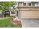 Lovely curb appeal of the tan home showcasing the two-car garage, brick accents, and manicured lawn at 16200 Hedgeway Dr, Parker, CO 80134