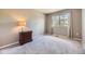 A neutral bedroom with a window that lets in natural light and a small nightstand with drawers at 1153 Berganot Trl, Castle Pines, CO 80108