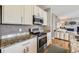 Well-lit kitchen featuring stainless steel appliances, granite countertops, and white cabinets adjacent to an inviting living area at 1153 Berganot Trl, Castle Pines, CO 80108