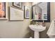 Chic powder room with a pedestal sink, stylish mirror, and decorative artwork, offering a touch of elegance and charm at 1153 Berganot Trl, Castle Pines, CO 80108
