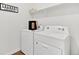 Functional laundry room with white washer and dryer, storage shelf and modern design at 4692 Hatcher Dr, Brighton, CO 80601