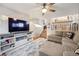 Bright living area features a large TV, stylish console, ceiling fan, and an open staircase leading to the kitchen at 13097 S Bonney St, Parker, CO 80134