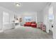 A bonus room is carpeted and features a red couch, toy shelving, and natural light at 601 Morrison Dr, Frederick, CO 80530