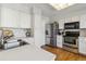 Well-lit kitchen featuring stainless steel appliances, white cabinets, and hardwood floors at 7373 E Iowa Ave # 1108, Denver, CO 80231