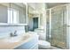 Clean and bright bathroom featuring a glass shower, white vanity and tiled walls, with large mirror at 7300 Beech St, Arvada, CO 80005