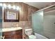 Bathroom featuring wood paneling, stone vanity, shower/tub with sliding door at 7300 Beech St, Arvada, CO 80005