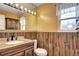 Charming bathroom with wood paneled walls, granite vanity, and large mirror with globe lighting at 7300 Beech St, Arvada, CO 80005