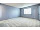 Simple blue bedroom featuring neutral carpet, one window with simple blinds, and a white door at 7300 Beech St, Arvada, CO 80005