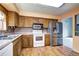 Traditional kitchen with oak cabinets, white appliances, stainless steel fridge, and wood-look flooring at 7300 Beech St, Arvada, CO 80005