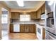 Traditional kitchen with wood cabinets, white appliances, stone countertops, and wood-look flooring at 7300 Beech St, Arvada, CO 80005