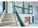 Carpeted staircase with teal railing leading to an upstairs landing with a view of the kitchen at 7300 Beech St, Arvada, CO 80005