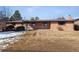 Backyard view of a single-story brick house with a wooden deck, covered patio, and expansive lawn at 4192 S Vrain St, Denver, CO 80236