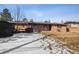 Backyard view of a single-story brick house with a wooden deck, covered patio, and expansive lawn at 4192 S Vrain St, Denver, CO 80236