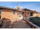 Backyard deck features wooden seating attached to a red brick house under a patio roof with trimmed green bushes at 4192 S Vrain St, Denver, CO 80236