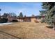 Backyard view of a single-story brick house with a wooden deck, covered patio, and expansive lawn at 4192 S Vrain St, Denver, CO 80236