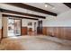 Open-concept living room with wood paneling, exposed beams and seamless kitchen access at 4192 S Vrain St, Denver, CO 80236