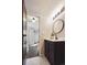 Stylish bathroom featuring a round mirror and a wooden door at 7705 W 87Th Dr, Arvada, CO 80005