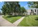 Townhome exterior featuring a well-manicured lawn with mature trees at 7705 W 87Th Dr, Arvada, CO 80005
