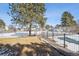 View of the community tennis court and pool area, surrounded by a secure fence and mature trees at 7705 W 87Th Dr, Arvada, CO 80005