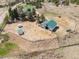 This aerial shows a barn with green roof, a trailer and metal outbuilding enclosed in a fenced area on a mostly dry lot at 12160 Spring Creek Rd, Parker, CO 80138