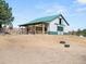 A well-maintained barn featuring green accents on its white exterior and adjacent paddock at 12160 Spring Creek Rd, Parker, CO 80138