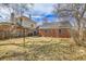 Backyard showcasing the brick home, mature trees, and partial fencing at 1448 Newport St, Denver, CO 80220