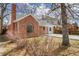Charming brick home with an arched window and gray roof, set against a backdrop of mature trees at 1448 Newport St, Denver, CO 80220
