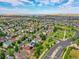 Expansive aerial view showcasing a well-planned community with green spaces, curved streets, and a distant lake at 26032 E Geddes Cir, Aurora, CO 80016