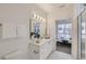 Bright bathroom with large mirror, vanity with sink, white cabinets, and mosaic tile flooring leading to bedroom at 3500 S Corona St # 407, Englewood, CO 80113