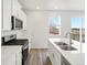 Bright kitchen features stainless steel appliances, white cabinetry and countertops, and wood flooring at 1937 S Coolidge Way, Aurora, CO 80018