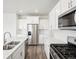 Bright kitchen features stainless steel appliances, white cabinetry and countertops, and wood flooring at 1937 S Coolidge Way, Aurora, CO 80018