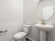 Bright powder room featuring a pedestal sink with brushed gold faucet and a round mirror at 1937 S Coolidge Way, Aurora, CO 80018