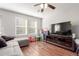 Inviting living room with wood floors, a comfortable gray sofa, a ceiling fan, and an entertainment center with a large television at 5830 Ceylon St # B, Denver, CO 80249