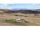 Picturesque aerial view features a farm house with mountain backdrop at 12747 Bestview Dr, Larkspur, CO 80118