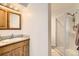 Well-lit bathroom features wood vanity with sink, tiled countertop, mirror and walk-in glass enclosed shower at 10408 Strasburg Way, Parker, CO 80134