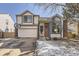 Two-story home featuring tan siding with a brick accent, large window, and a two-car garage at 10408 Strasburg Way, Parker, CO 80134