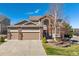 Charming front exterior featuring a brick facade, well-manicured lawn, and a three-car garage at 1863 Rose Petal Ct, Castle Rock, CO 80109