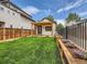 Landscaped backyard with lush lawn, pergola, garden beds, black metal fence, and a cozy outbuilding at 2849 S Bannock St, Englewood, CO 80110