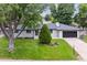 Charming single-story home with a manicured lawn, lush trees, and a modern dark-colored garage door at 210 E Graves Ave, Centennial, CO 80121