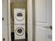 A compact laundry area features a stacked washer and dryer, maximizing space with white appliances and contrasting tile flooring at 191 Clayton Ln # 402, Denver, CO 80206