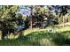 Lush green lawn and mature trees surround the exterior of a home and well in a wooded area at 7105 Flagstaff Rd, Boulder, CO 80302