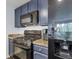 Close up of kitchen area with black appliances, granite counters and blue cabinets at 1441 Central St # 209, Denver, CO 80211
