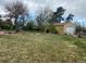 Spacious backyard with mature trees, a garage, a play structure, and lush green grass at 1123 S Quince Way, Denver, CO 80231