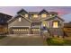 Beautiful two-story home with a three car garage and stone accents at dusk at 4009 Manorbrier Cir, Castle Rock, CO 80104